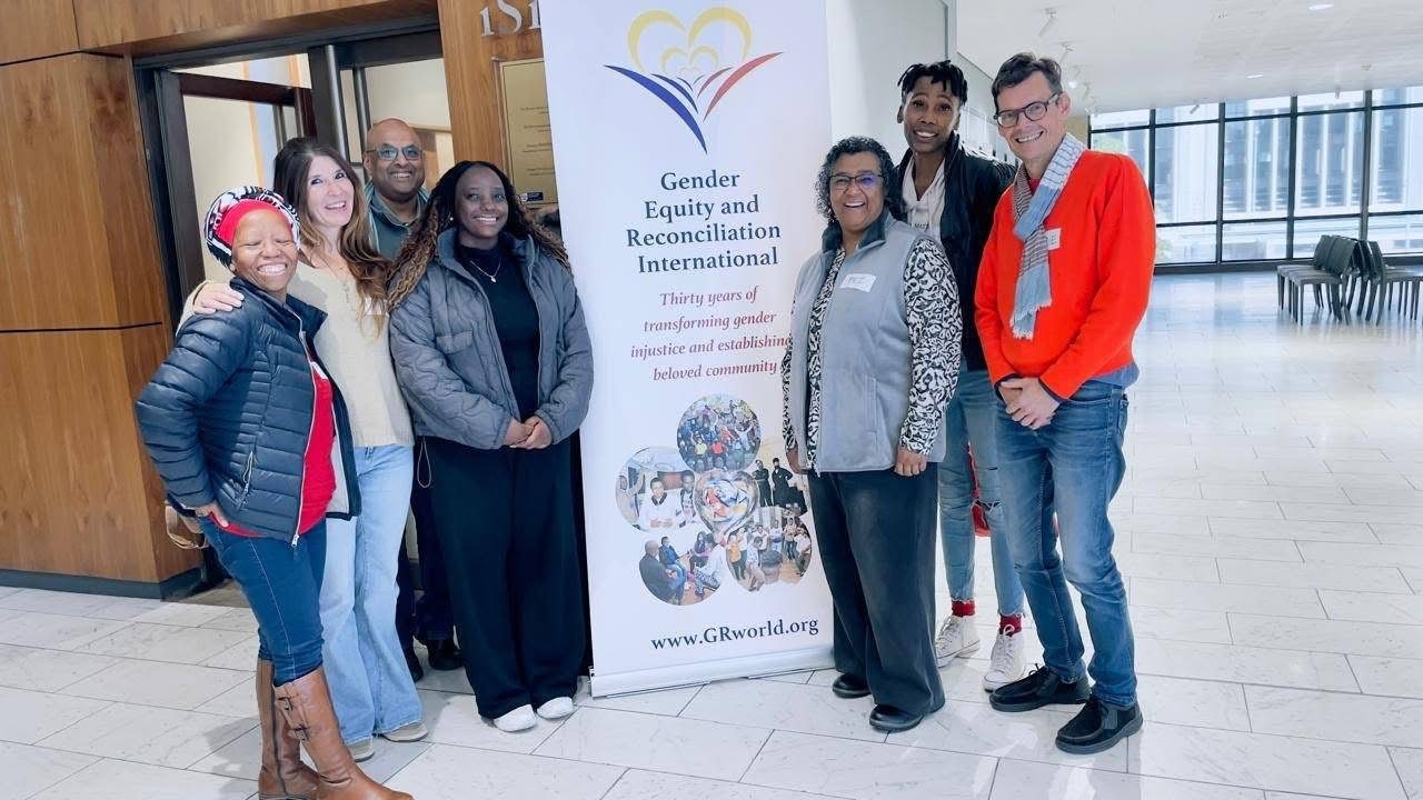 A group gathered beside a Gender Equity and Reconciliation International banner at the Artscape Theatre