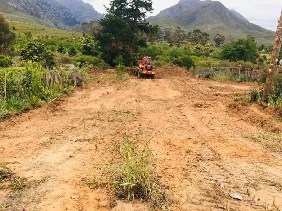 An earth-moving machine clearing the land, with mountains in the background